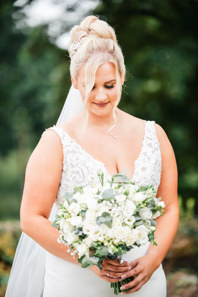 Bride looking at her bouquet at The Green Cornwall captured by Memories &amp; Milestones Photography