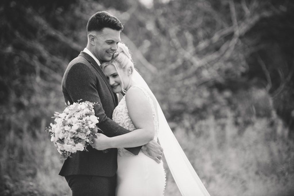 Newlyweds embracing in black and white at The Green Cornwall captured by Memories &amp; Milestones Photography