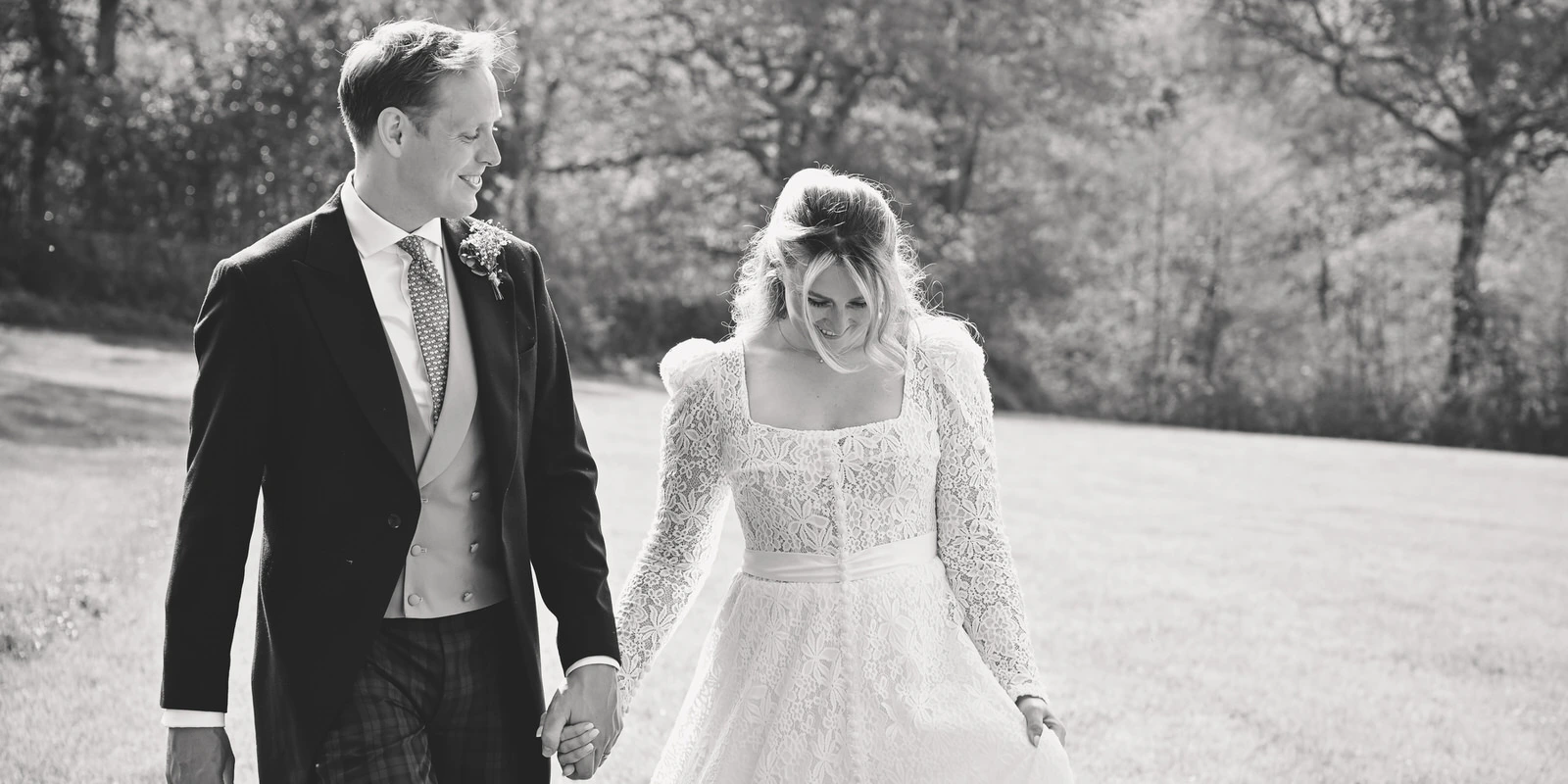 newlywed couple walking hand in hand in the countryside